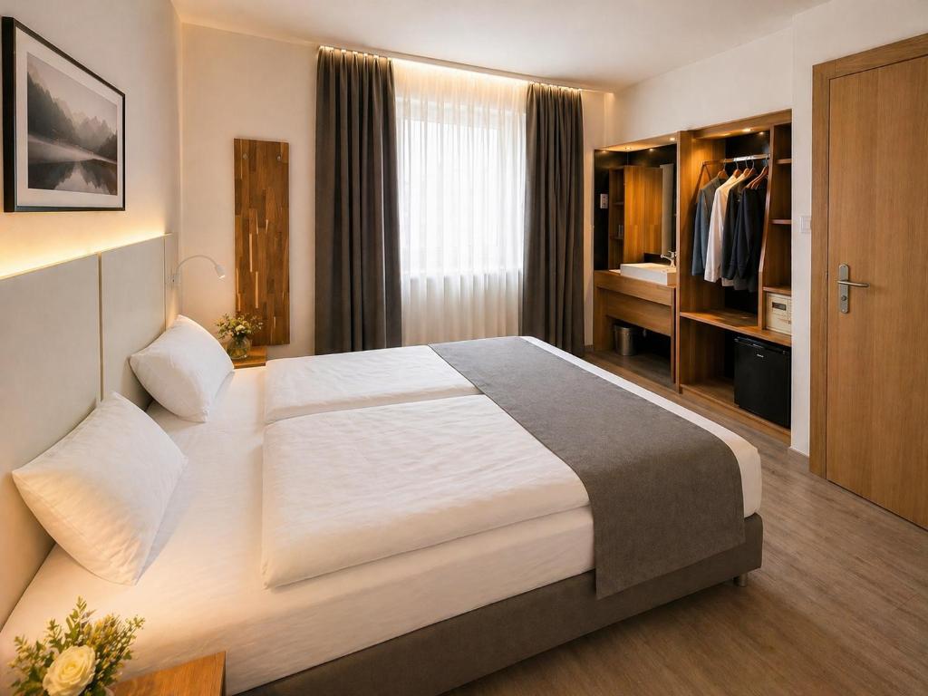 Modernes Klassik-Doppelzimmer im Hotel Drei Könige in Chur, mit einem ordentlich gemachten Bett, weißer Bettwäsche, einem grauen Bettläufer, einem Schreibtisch aus Holz und warmer, indirekter Kopfteil-Beleuchtung.