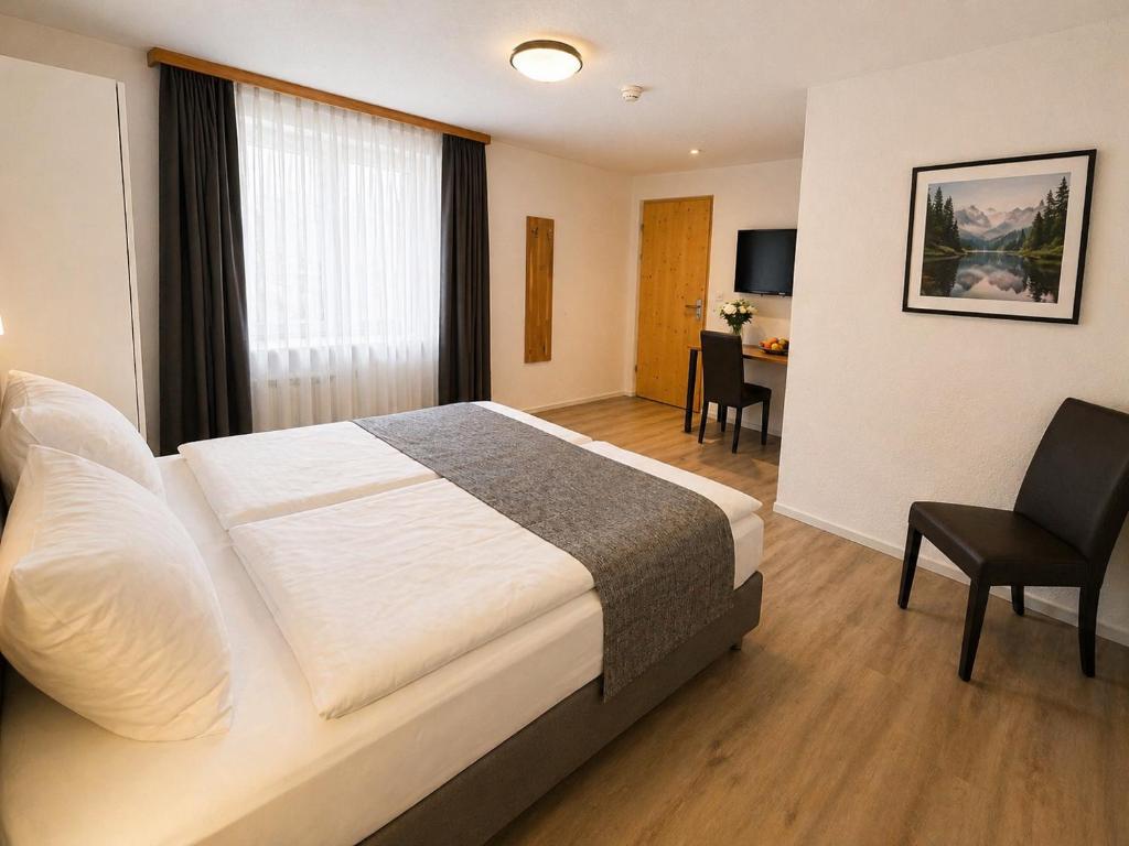 Ruhiges Standard-Doppelzimmer zum Innenhof im Hotel Drei Könige in Chur, ausgestattet mit einem bequemen Bett mit makellos weißer Bettwäsche, einem dunkelgrauen Läufer, modernem Parkettboden, einem Schreibtisch und einem wandmontierten Fernseher.